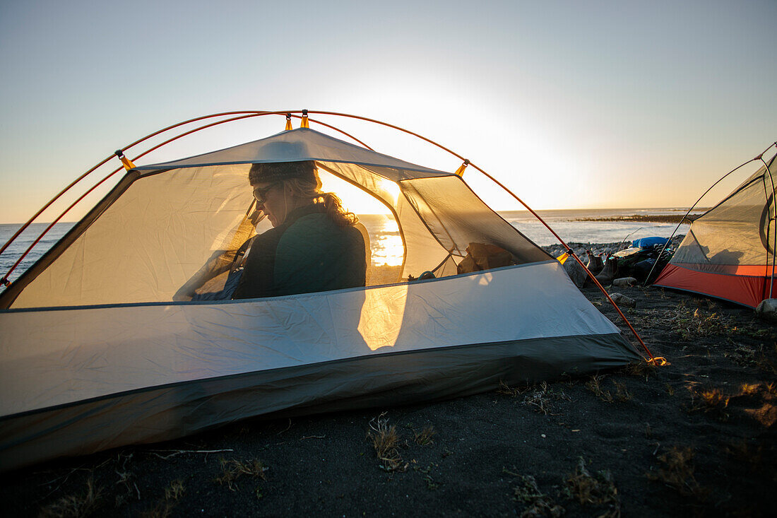 Woman sitting in camping tent on beach, Big Flat, Lost Coast Trail, Kings Range National Conservation Area, California, USA