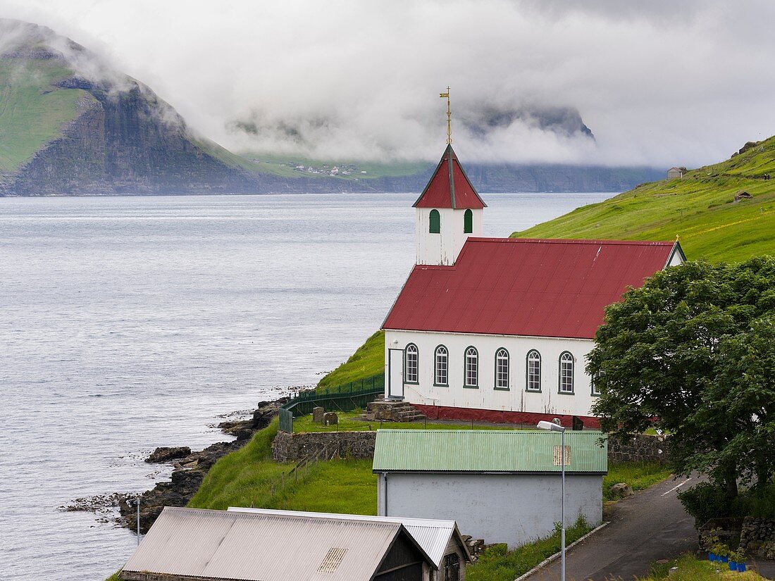 The island of Kunoy with village Kunoy and church. In the background island Kalsoy. Nordoyggjar (Northern Isles) in the Faroe Islands, an archipelago in the north atlantic. Europe, Northern Europe, Scandinavia, Denmark, Faroe Islands.