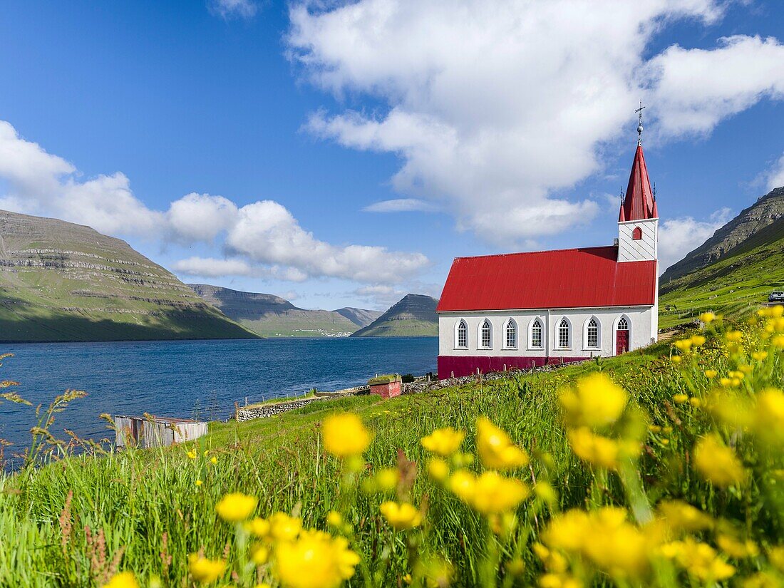 The church in village Husar on Kalsoy, in the background the island of Bordoy and Klaksvik. Nordoyggjar (Northern Isles) in the Faroe Islands, an archipelago in the north atlantic. Europe, Northern Europe, Scandinavia, Denmark, Faroe Islands.