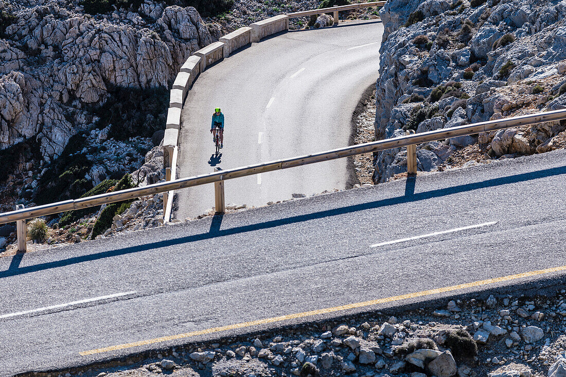 Eine Radfahrerin auf einer Serpentinenstrasse,  Cap Formentor, Tramuntana Gebirge, Mallorca, Spanien