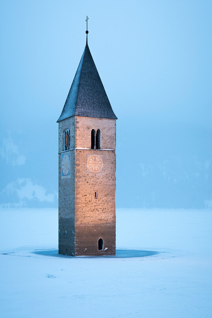 The submerged bell tower of Curon Venosta, province of Bolzano, Alto Adige district, Italy, under a snowfall