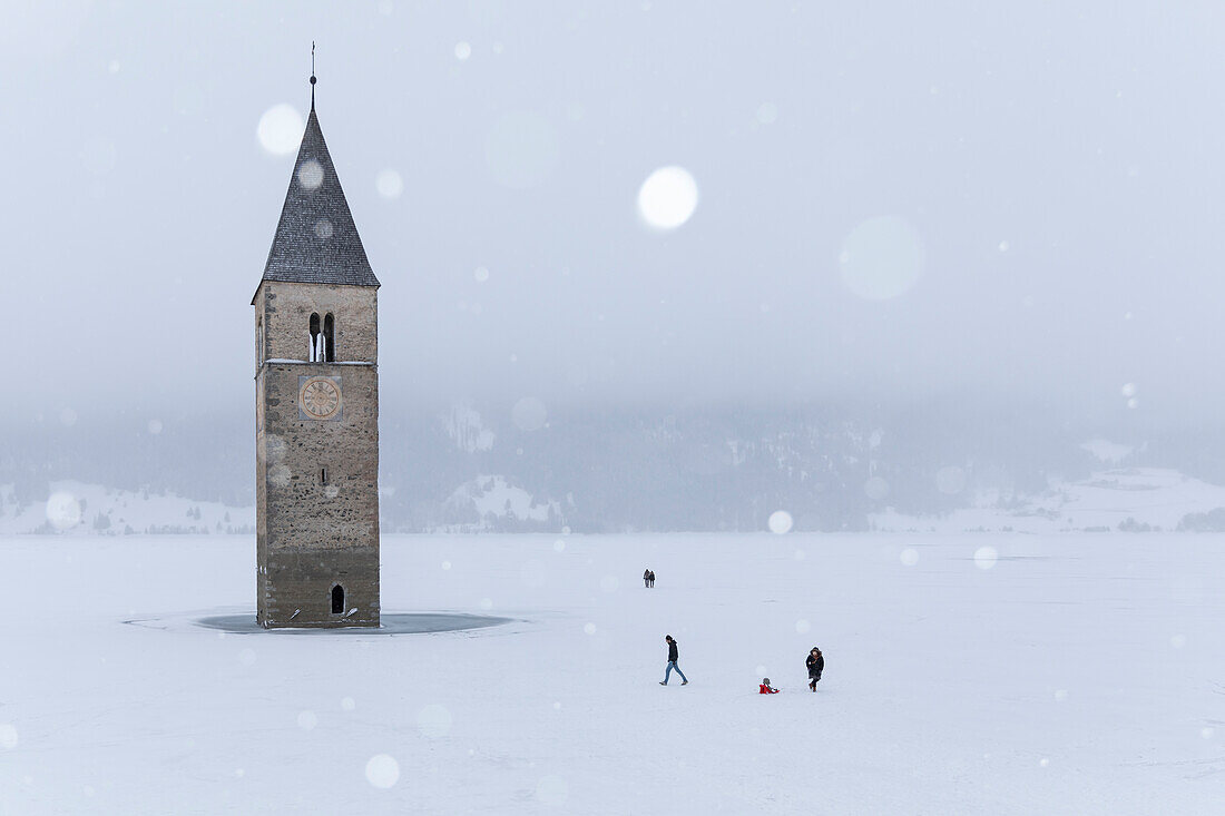 The submerged bell tower of Curon Venosta, province of Bolzano, Alto Adige district, Italy, under a snowfall