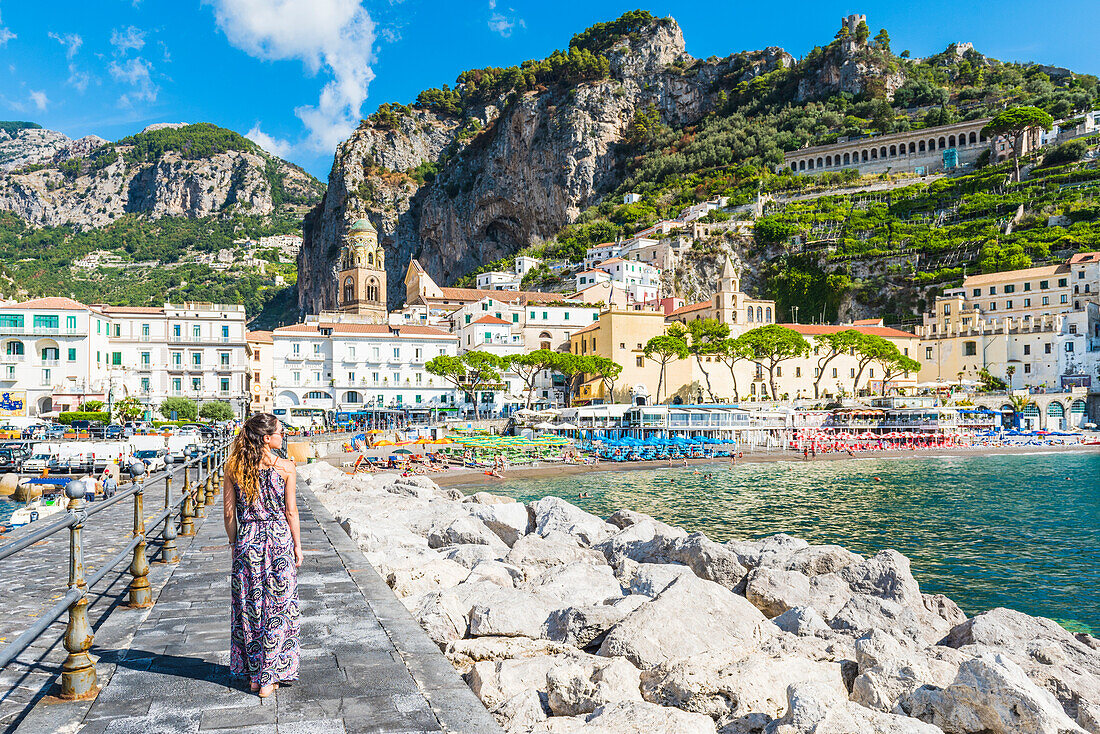 Amalfi, Amalfi coast, Salerno, Campania, Italy. Young woman strolling along the pier of Amalfi village