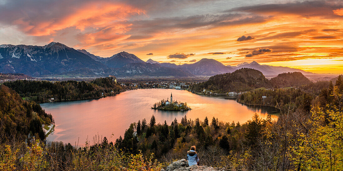 Elevated view of lake Bled at sunrise. A young woman admires the view. Bled, Upper Carniola, Slovenia
