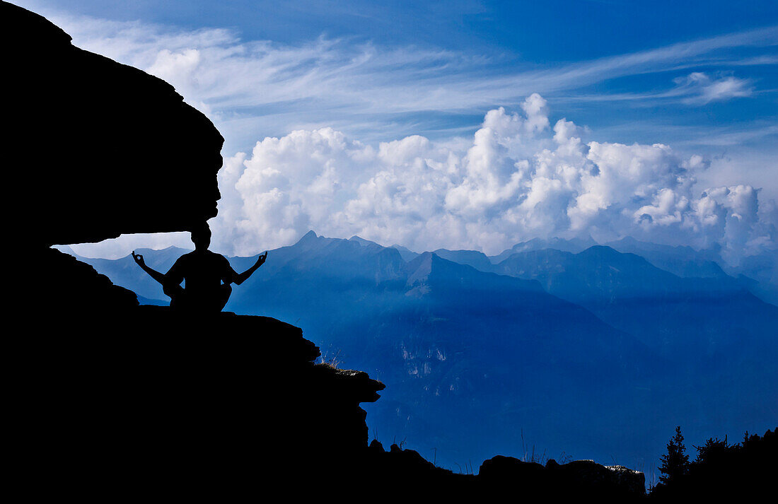 Man practice Zen meditation on the rocks admiring the Lepontine Alps from Brogoldone refuge, Lumino, Canton of Ticino, Switzerland, Europe