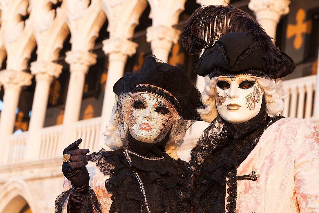 A couple of typical mask of Carnival of Venice with Ducal Palace on background, Venice, Veneto, Italy