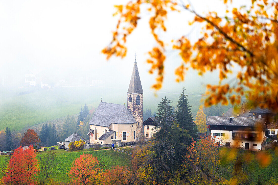 Church of Santa Magdalena in the autumn mist. Funes Valley, South Tyrol, Dolomites, Italy