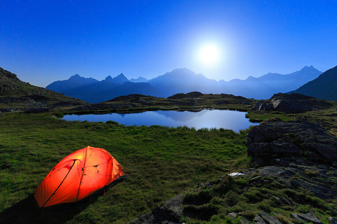 Night of full moon with camping tend on the shore of a small lake. Alpe Fora, Valmalenco, Valtellina, Lombardy, Italy.