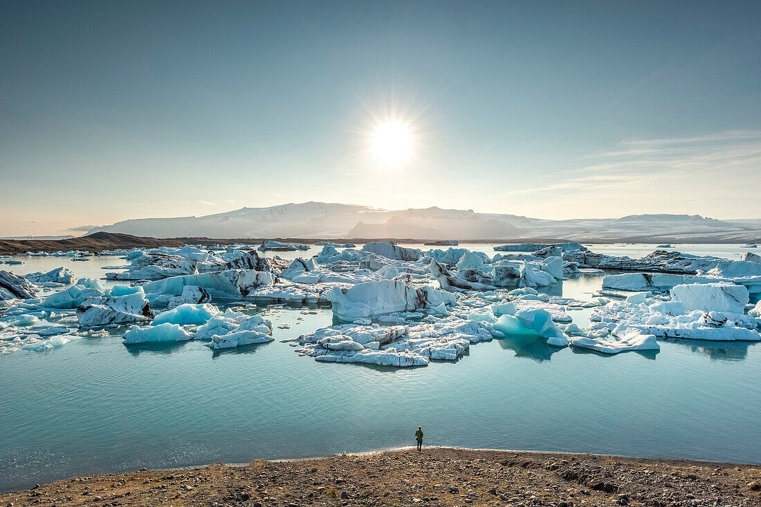 Person admiring icebergs at glacier lagoon of Jokulsarlon. Eastern Iceland, Iceland