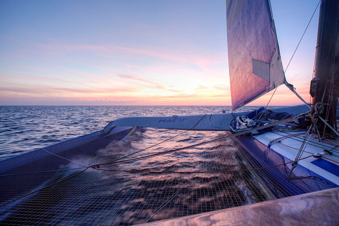 View from onboard of sailing trimaran at sunset, Atlantic Ocean, Brittany, France
