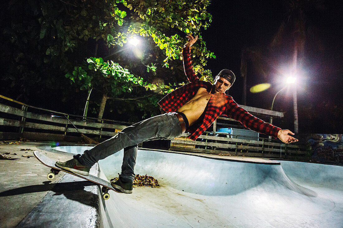 Side view of man skateboarding in illuminated skate park at night, Jimbaran, Bali, Indonesia