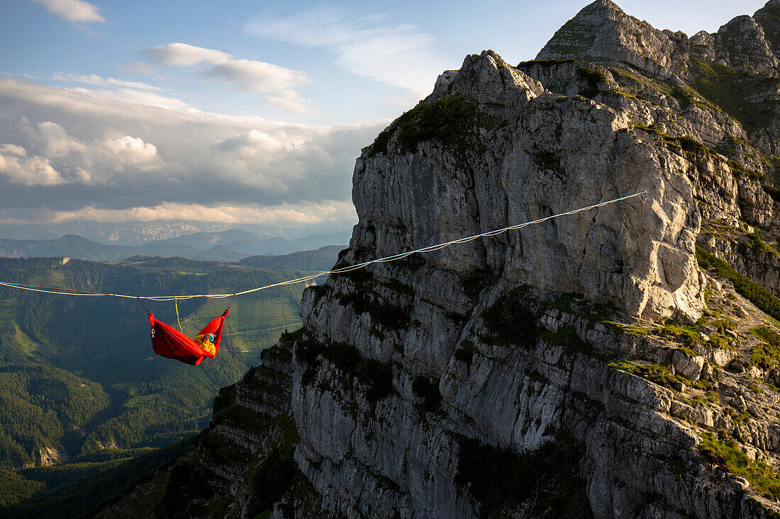 Person sleeping in hammock and hanging on line above mountains in Lower Austria, Austria