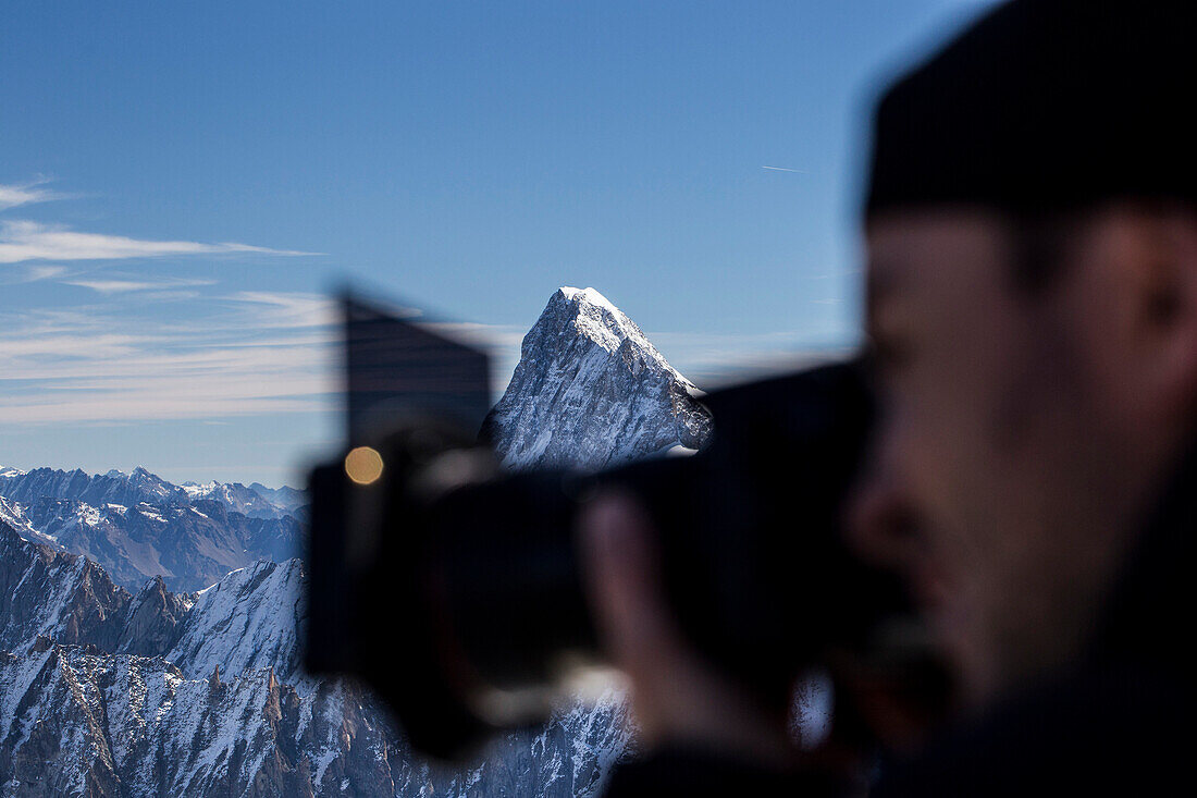 Photographer taking pictures in Mont Blanc range with mountain peak in background, Chamonix-Mont-Blanc, Haute-Savoie, France