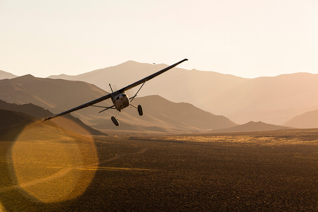 Kevin Quinn's highly modified 1953 Cessna 180 Skywagon flies in late afternoon light in the Nevada Desert.