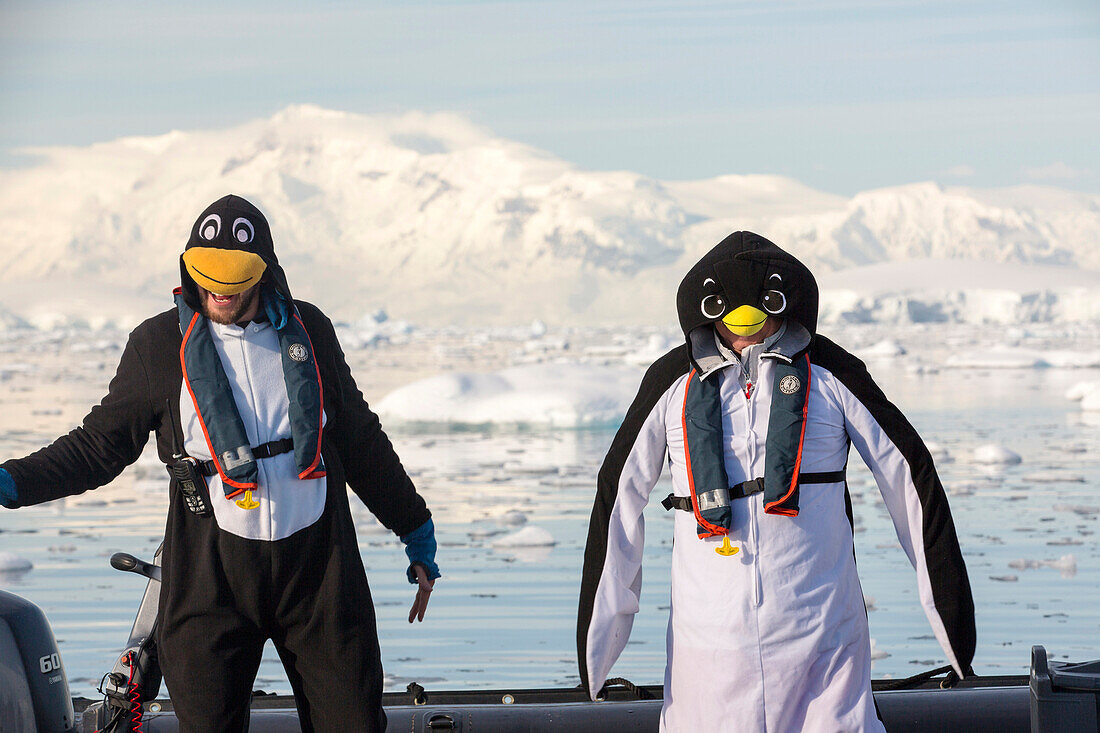 Crew members of an expedition cruise to Antarctica in a Zodiak in Fournier Bay in the Gerlache Strait on the Antarctic peninsula, dressed up as penguins. The Antarctic peninsula is one of the most rapidly warming areas on the planet.