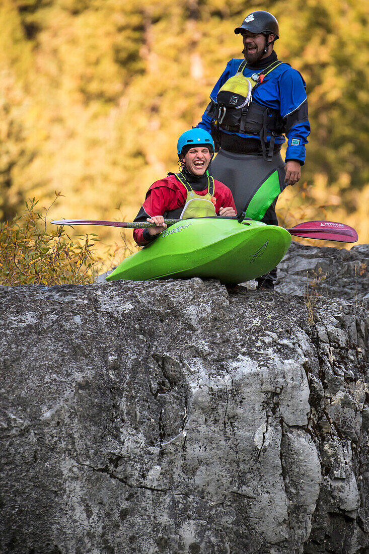 Kayaker laughing while preparing to drop into river from top of rock, Jackson Hole, Wyoming, USA
