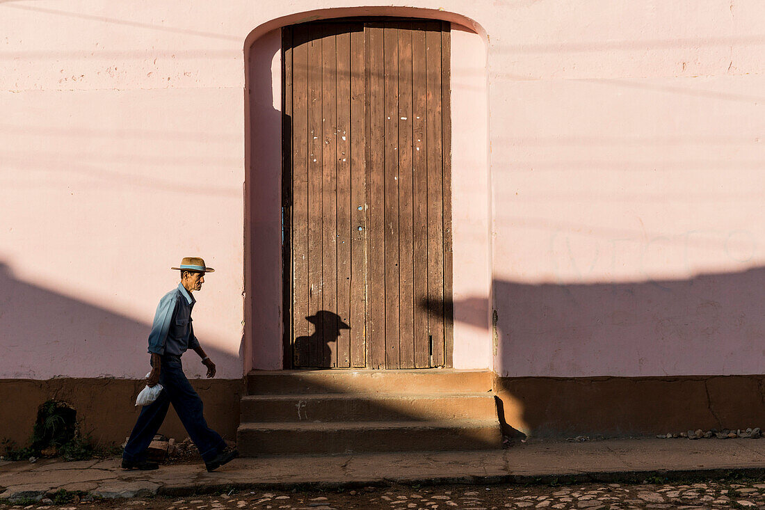 Side view of senior man walking in street outside building, Trinidad, Sancti Spiritus Province, Cuba