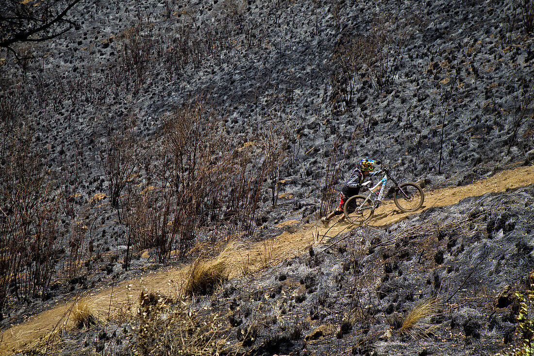 Biker pushing bicycle up hillside dirt road, Tenango, State of Mexico, Mexico