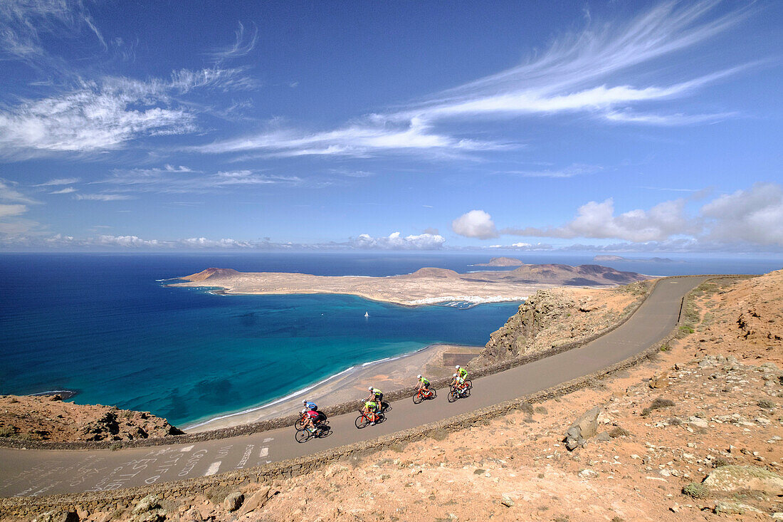 Group of cyclists pedaling on coastal road, Lanzarote, Canary Islands, Spain
