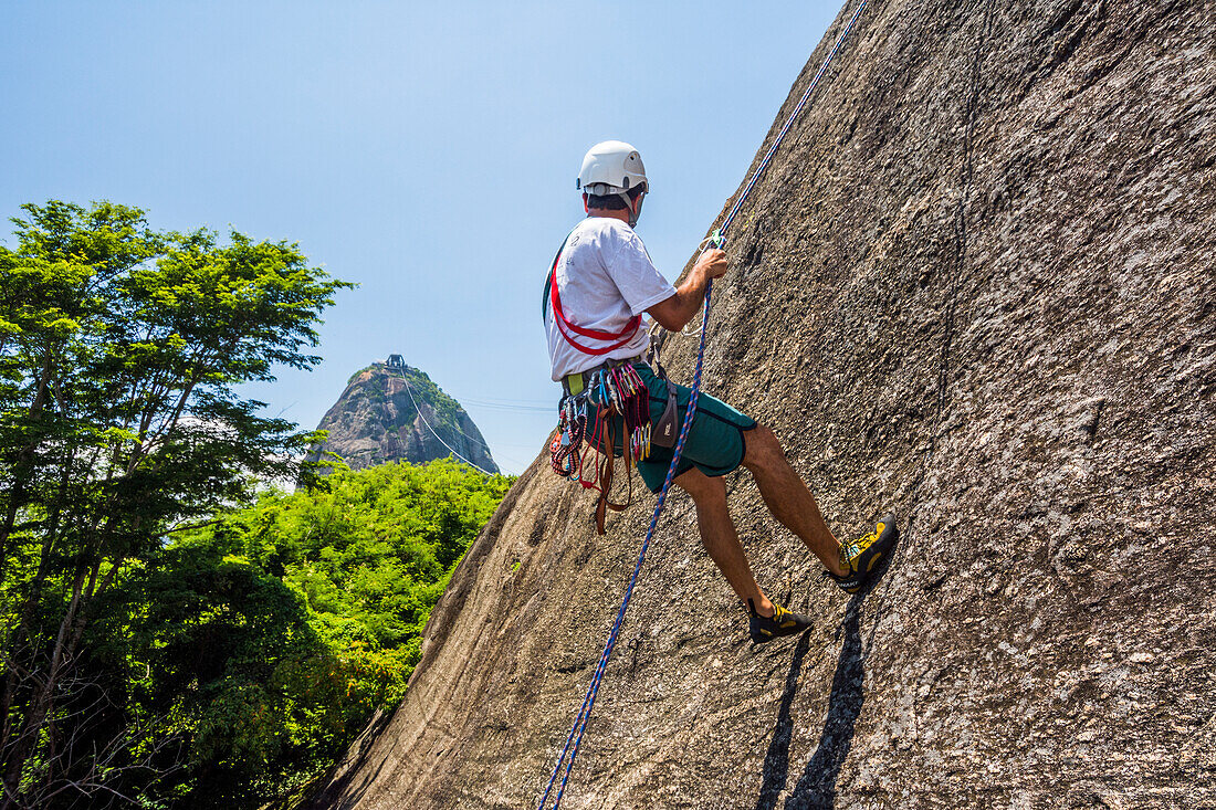Side view of adventurous man rock climbing Morro da Urca next to the Sugarloaf Mountain, Rio de Janeiro, Brazil