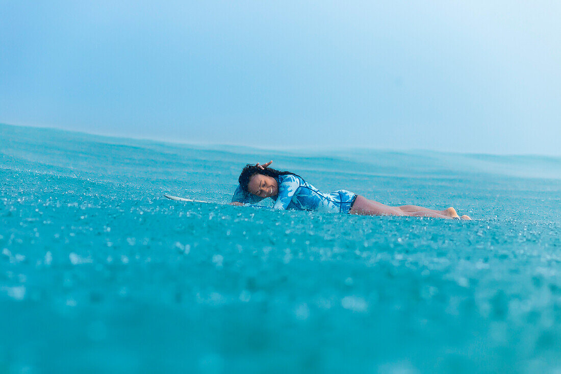Smiling woman lying on surfboard in sea