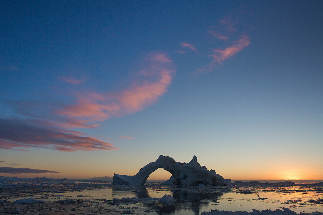 Dramatic arch formed in an iceberg that came from the Ilulissat Icefjord. Climate change is amplifying the speed in which the glaciers of Greenland are calving icebergs, which can be found around Ilulissat in abundance.
