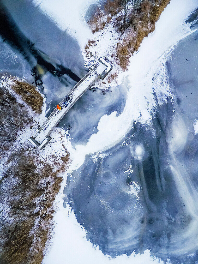 Aerial view of mountain bikers on bridge over frozen lake, South Kingstown, Rhode Island, USA