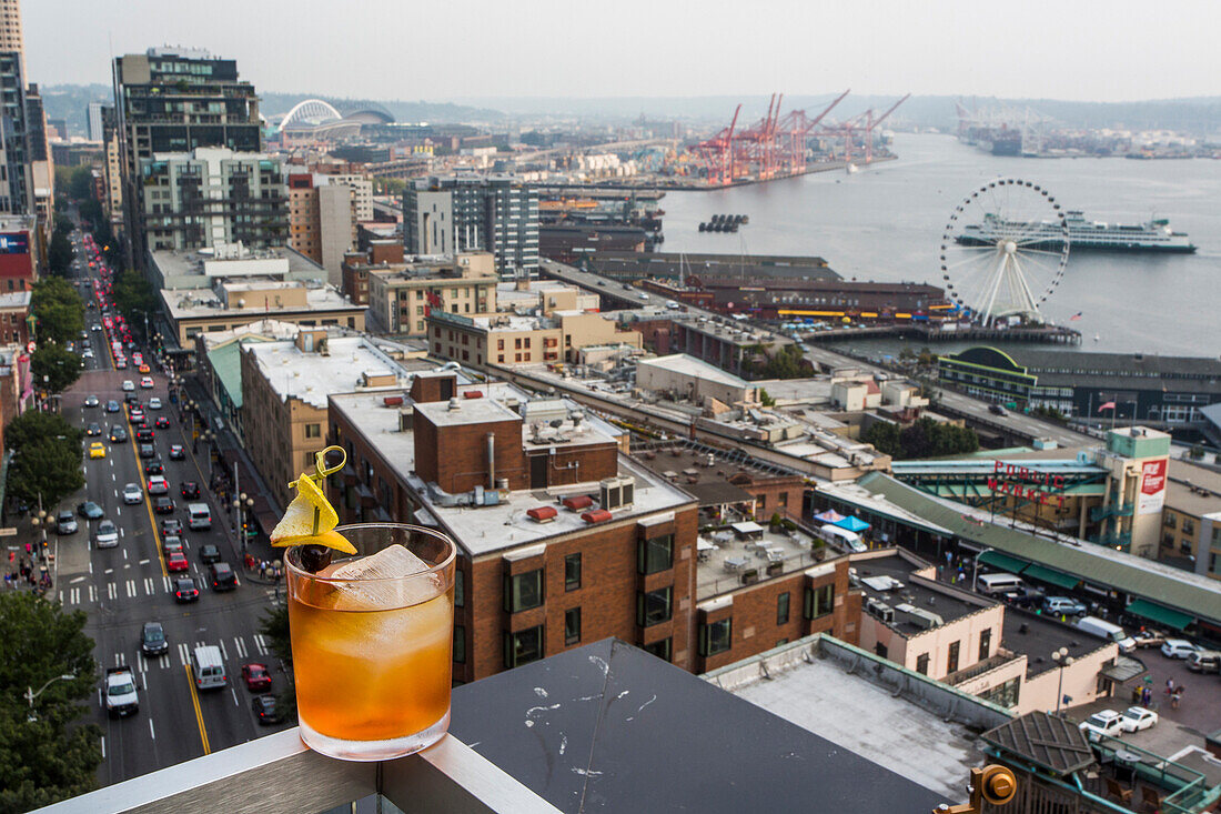 The skyline of Seattle, WA from the balcony of a downtown hotel and a cocktail in the foreground.