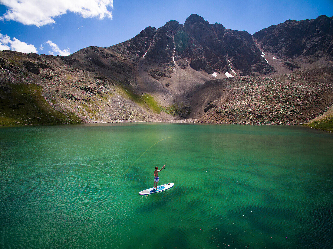Aerial view of young male fly fishing from his paddle board on high alpine lake in Aspen, Colorado, USA