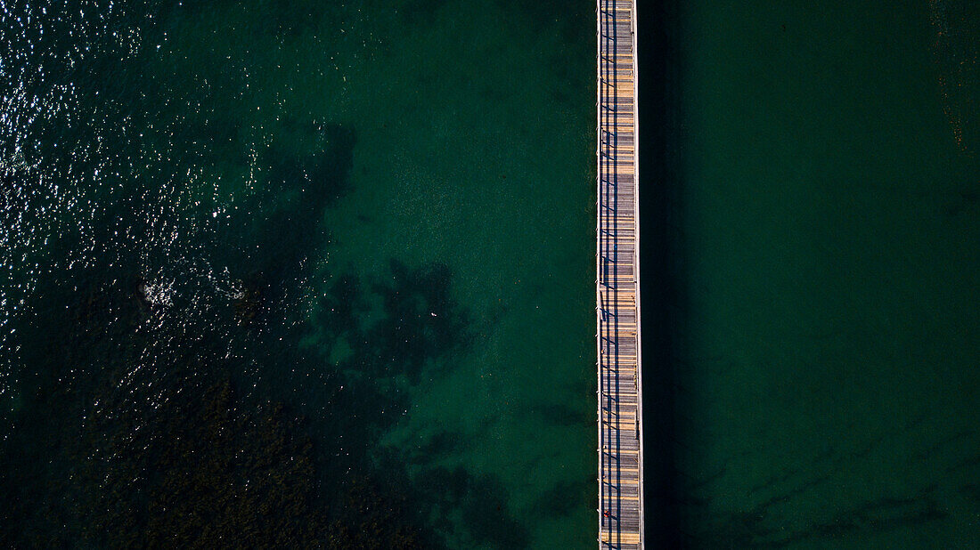 Minimalist photograph with aerial view of long pier in sea