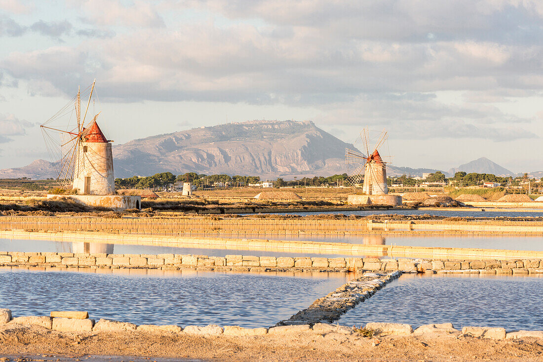 Salt pans with rows of tanks and two fully functional windmills on the coast connecting Marsala to Trapani, Trapani province,Sicily,Italy