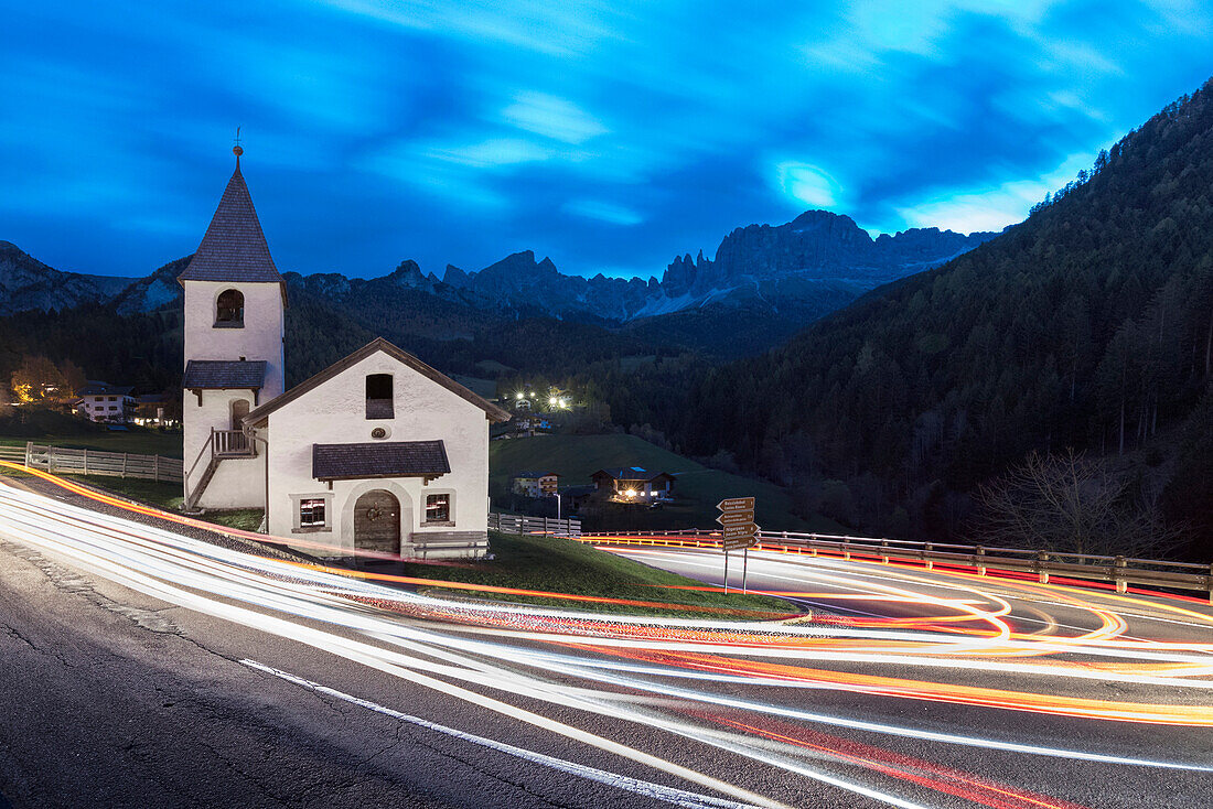 Lights of car trails around the Church of San Cipriano, Tires Valley, Dolomites, South Tyrol, Bolzano province, Italy
