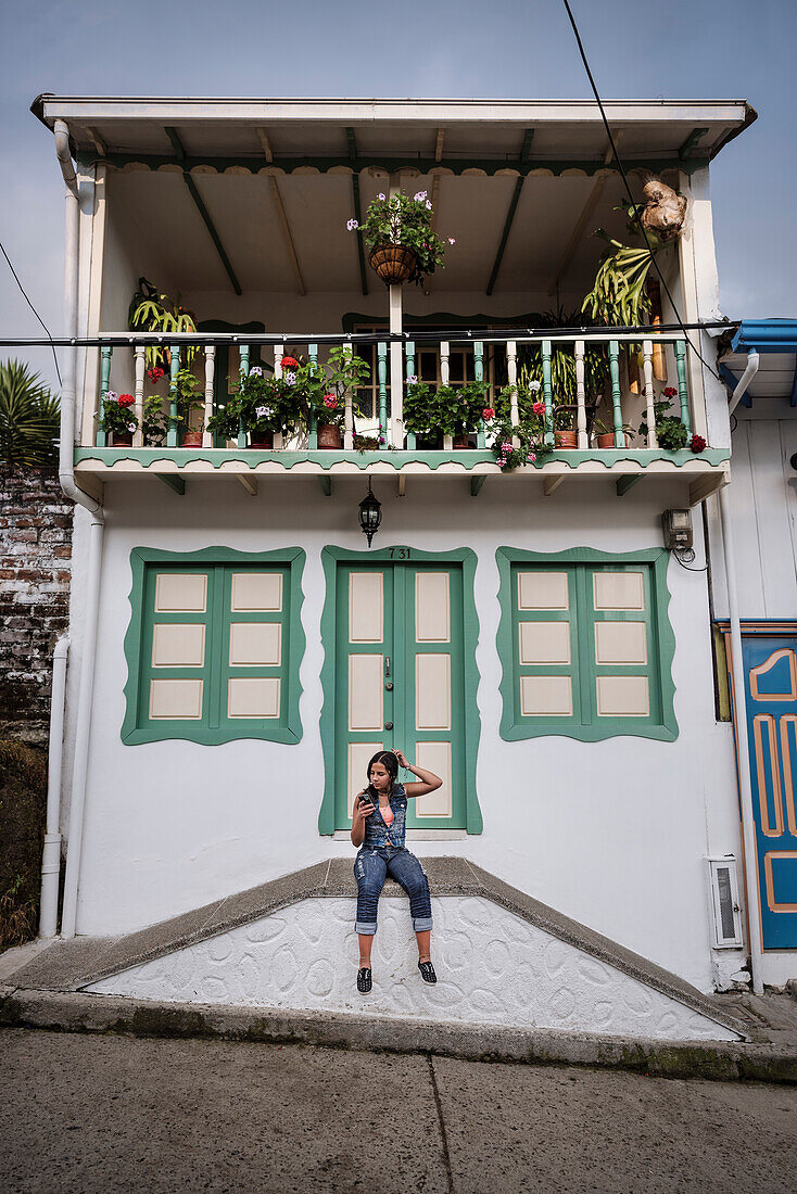 young woman getting her hair done with smartphone camera in front of colonial building, Salento, UNESCO World Heritage Coffee Triangle, Departmento Quindio, Colombia, Southamerica