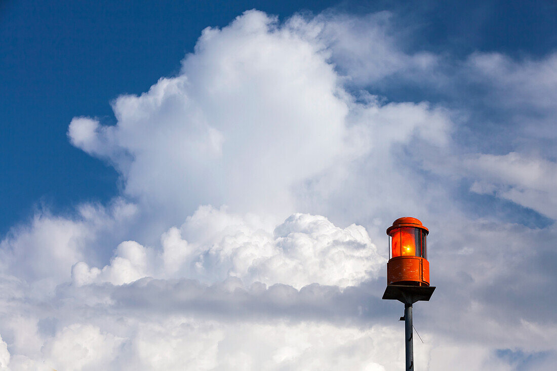 Sturmwarn-Leuchte am Chiemsee bei Prien, dahinter weiße Wolken am blauen Himmel