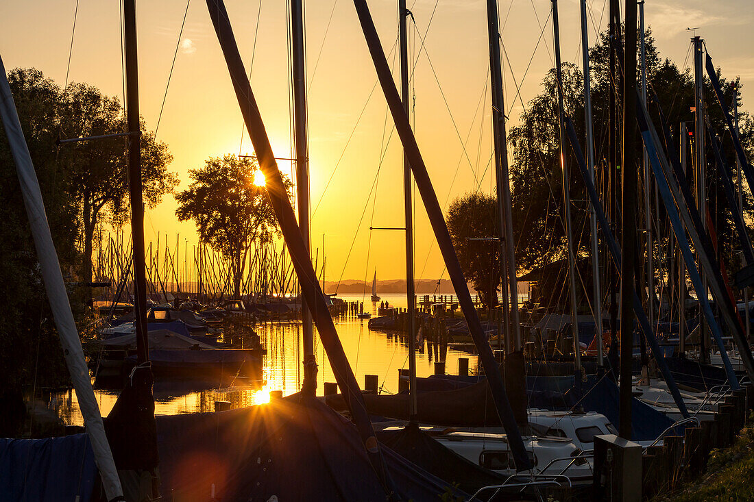 View between sail masts on waste electrical and sailboats in the Port field in the sunset at the Chiemsee Wieser