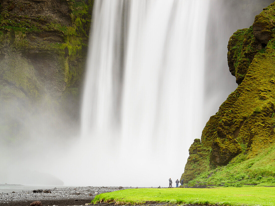 Menschen vor dem riesigen Skogafoss Wasserfall, Südküste, Island