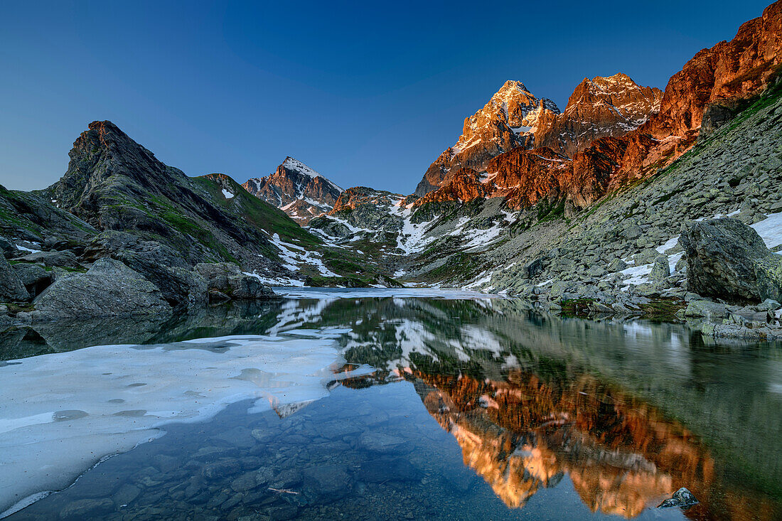 Monviso in alpenglow reflecting in mountain lake, Monte Viso, Monviso, valley valle di Po, Cottian Alps, Piedmont, Italy