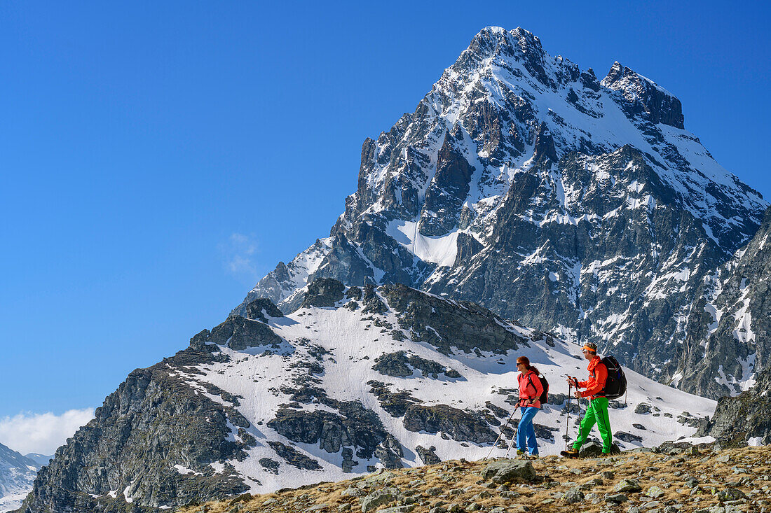 Man and woman hiking at Giro di Monviso and looking into valley, Monviso in background, Giro di Monviso, Monte Viso, Monviso, valley valle di Po, Cottian Alps, Piedmont, Italy