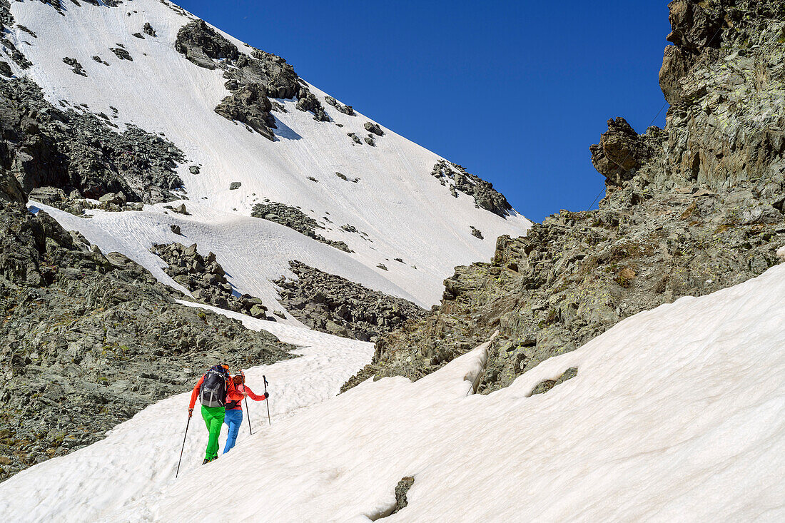 Mann und Frau beim Wandern auf Giro di Monviso steigen durch Schnee zum Colle delle Traversette auf, Giro di Monviso, Monte Viso, Monviso, Valle di Po, Cottische Alpen, Piemont, Italien