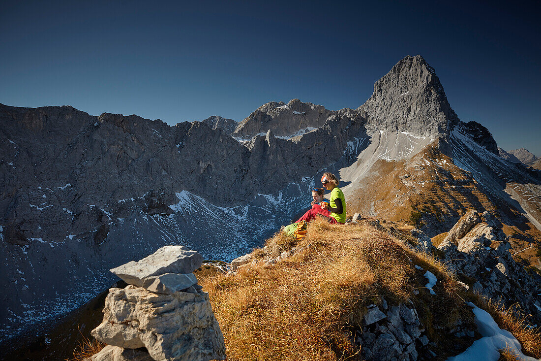 two women having a break on the ridge of Schafjoechl, Lamsenspitze in the back,  Eastern Karwendel Range, Tyrol, Austria