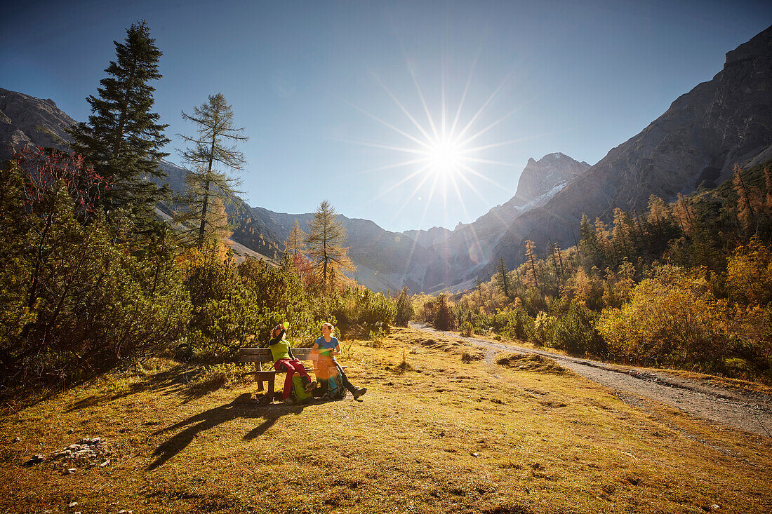 two women having a break while hiking in Falzthurn valley in autumn ,  Eastern Karwendel Range, Tyrol, Austria