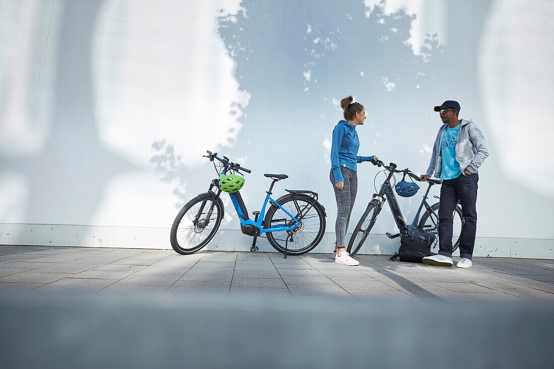 junge Frau und junger Mann Paar mit eBikes in der Stadt, München, Bayern, Deutschland