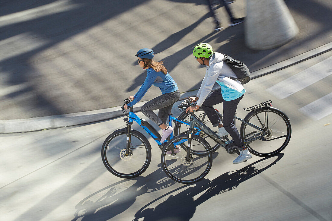 junge Frau und junger Mann Paar auf eBikes in der Stadt, München, Bayern, Deutschland