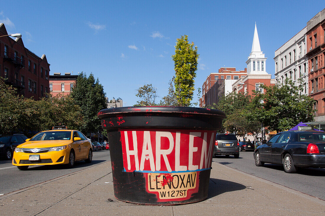 giant pot of flowers in the colors of harlem along lenox avenue with a new york taxi and the bell of a gospel church, harlem, manhattan, new york city, new york, united states, usa
