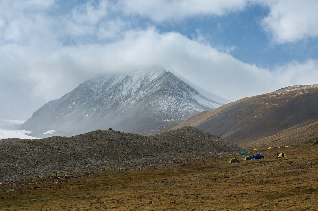 tents in the base camp of mount khuiten, the fog-covered mount malchin in the background, tavan bogd massif, altai, bayan-olgii province, mongolia