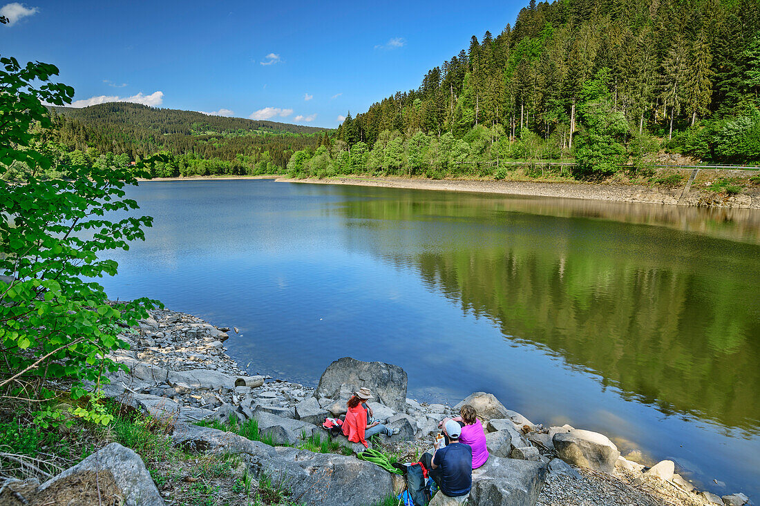 Three persons sitting at beach of Alb-Stausee and having a break, Alb-Stausee, Albsteig, Black Forest, Baden-Wuerttemberg, Germany