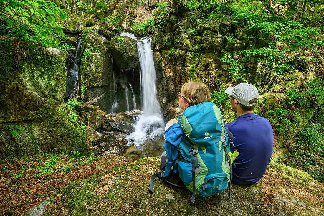 Man and woman hiking looking towards waterfall, waterfall Hoellbach, Albsteig, Black Forest, Baden-Wuerttemberg, Germany