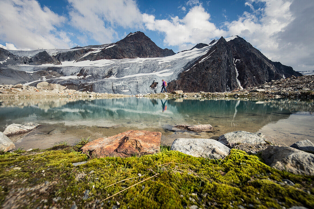 Hiker wanders at a mountain lake with the Pitztal Glacier in the background, E5, Alpenüberquerung, 4th stage, Skihütte Zams,Pitztal,Lacheralm, Wenns, Gletscherstube, Zams to  Braunschweiger Hütte, tyrol, austria, Alps
