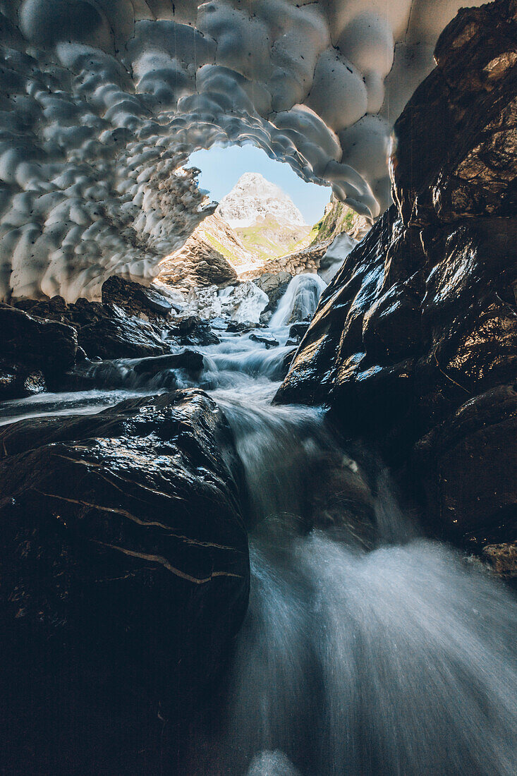 mountain river through old snow cave , E5, Alpenüberquerung, 1st stage Oberstdorf Sperrbachtobel to Kemptnerhütte, Allgäu, Bavaria, Alps, Germany