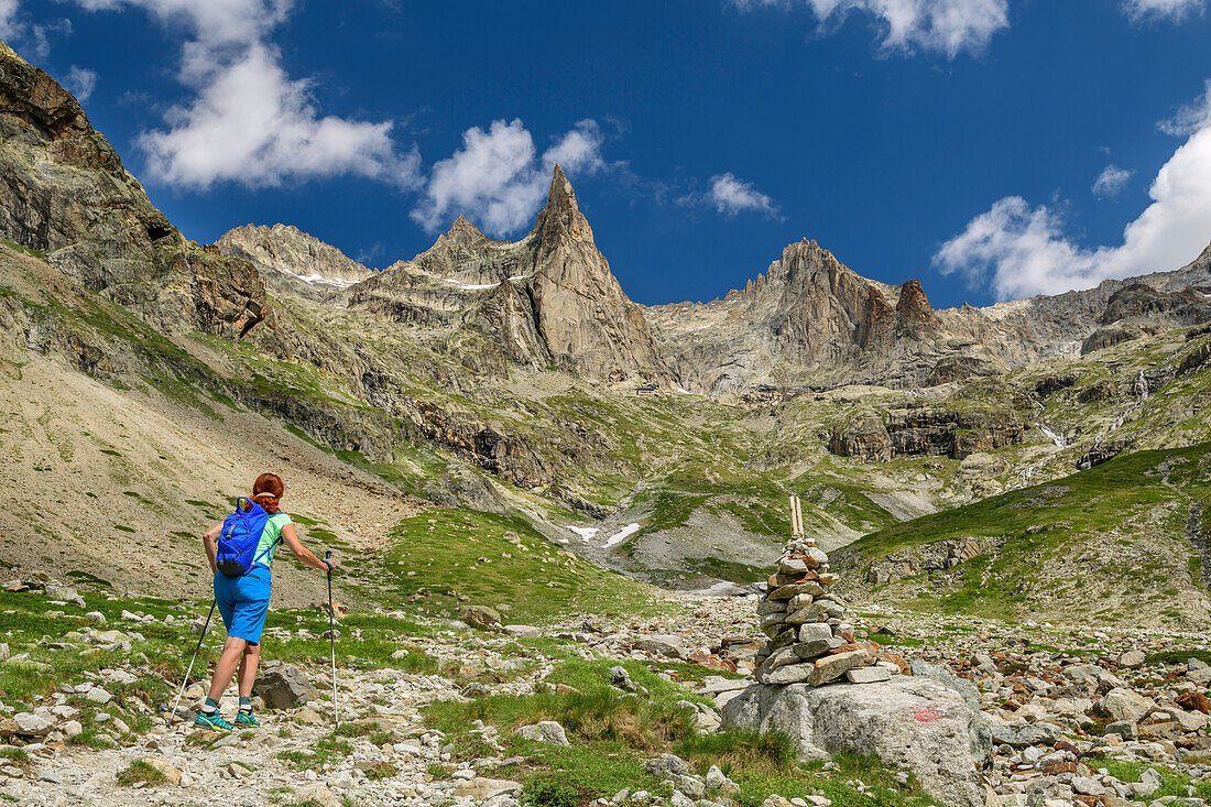 Woman while hiking rises for the refuge du sore Iller, Aiguille Dibona Orientale and Aiguille du sore Iller in the background, Ecrins, Ecrins National Park, Dauphiné, Dauphiné, Hautes Alpes, France